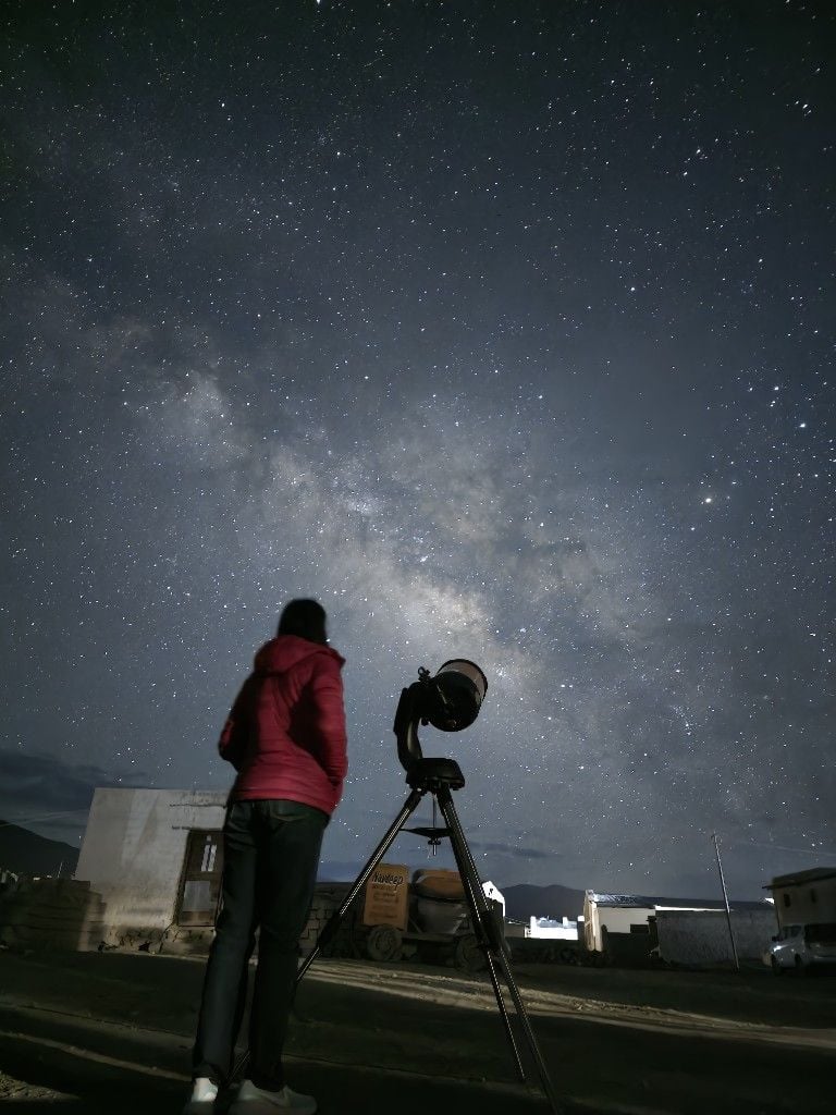 A traveller and telescope under the Milky Way at Hanle