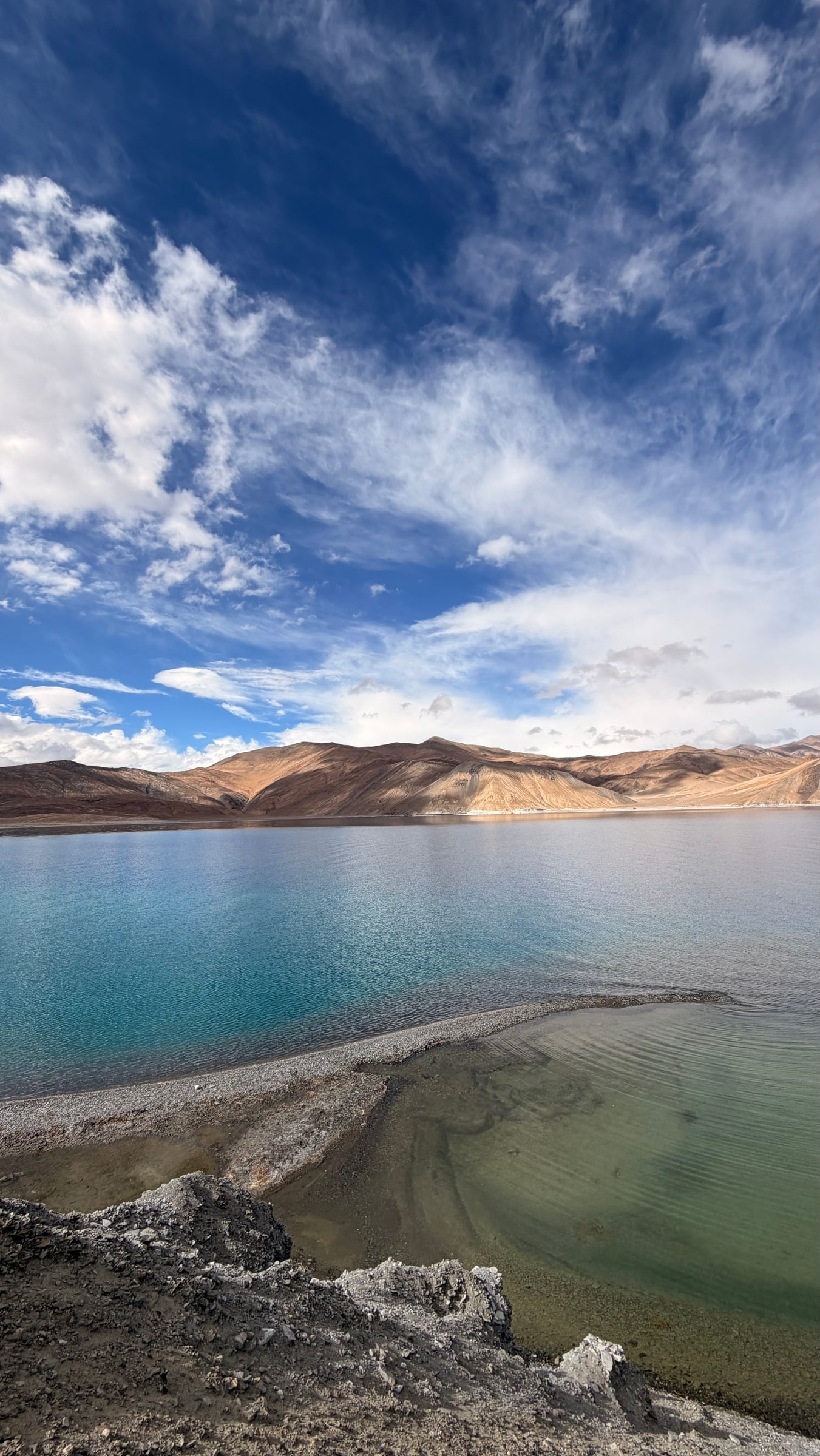 Turquoise and green shallows at Pangong Tso beside a pebble spit