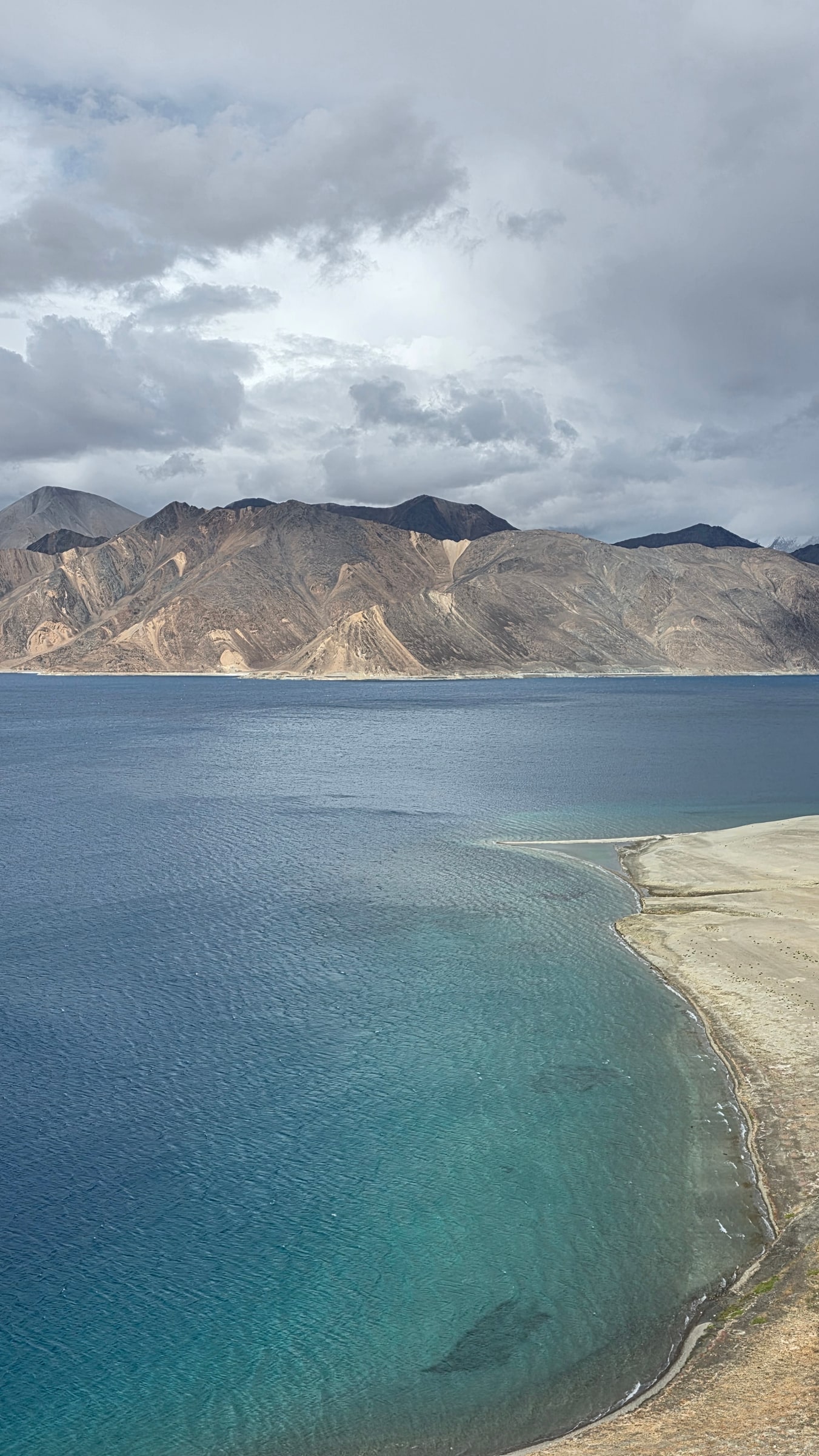 Navy and turquoise bands across Pangong Tso under cloud