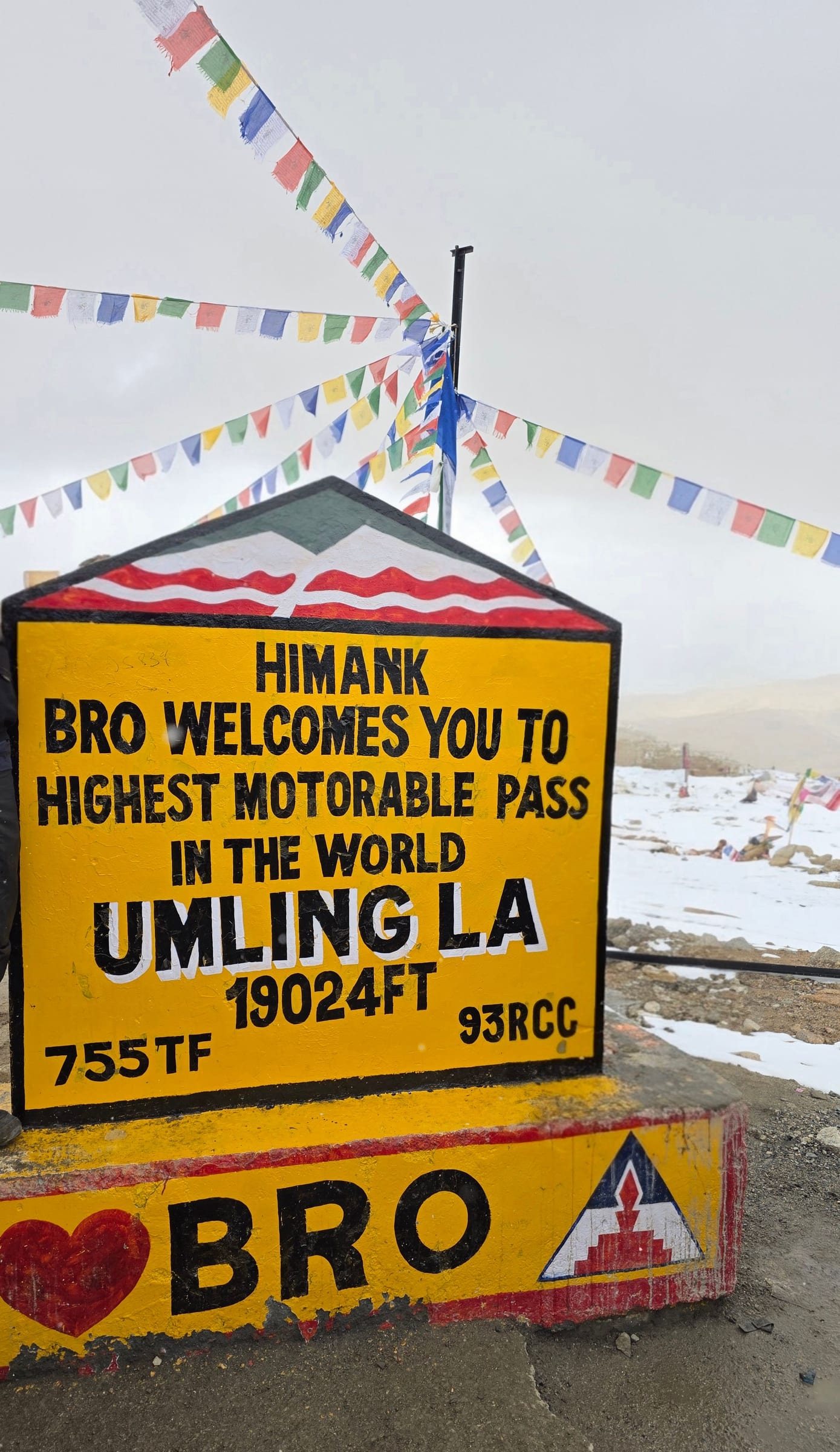 The Umling La summit sign reading 19,024 ft, with prayer flags behind it