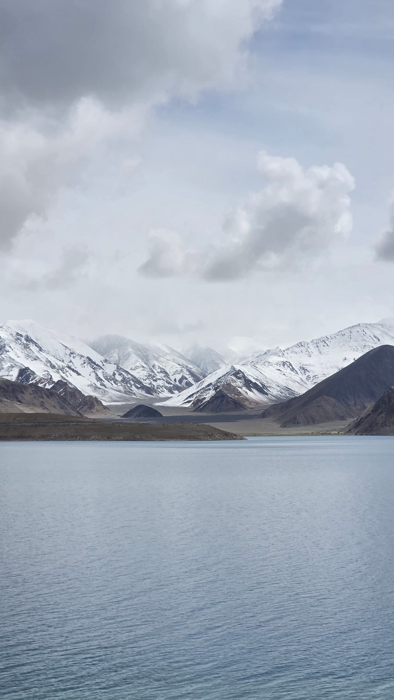 A still high-altitude lake beneath snow peaks in Ladakh
